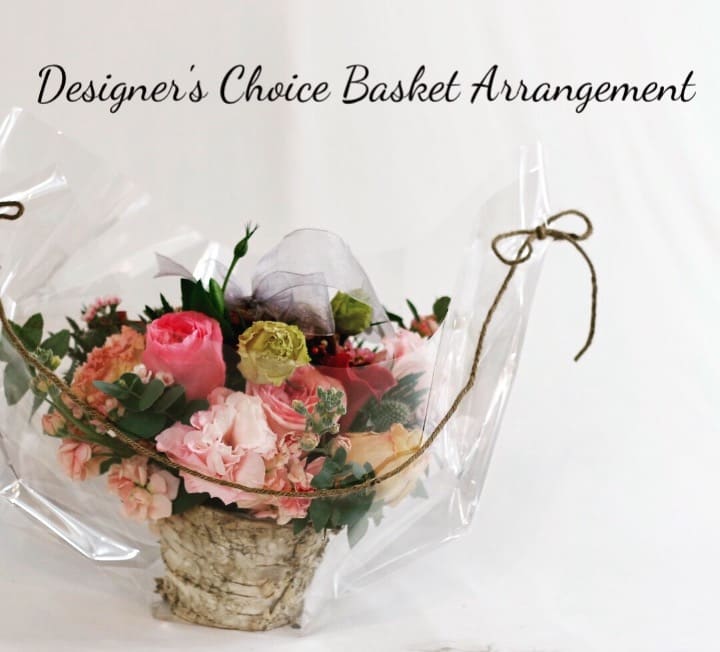 Basket arrangement of pink and peach flowers wrapped in clear plastic