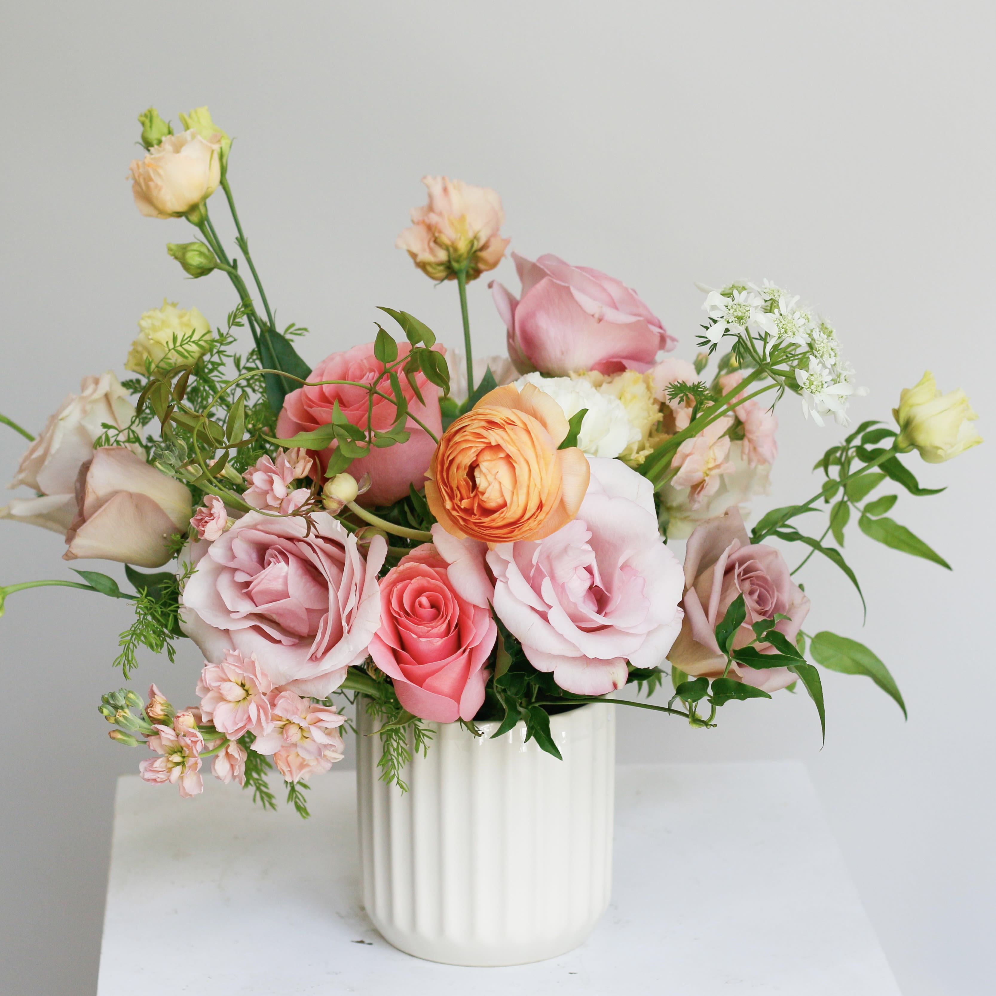 Pink and peach roses arranged in a white vase