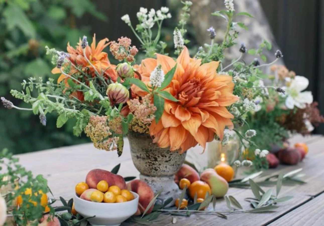 Orange dahlia arrangement in a rustic vase with airy wildflowers