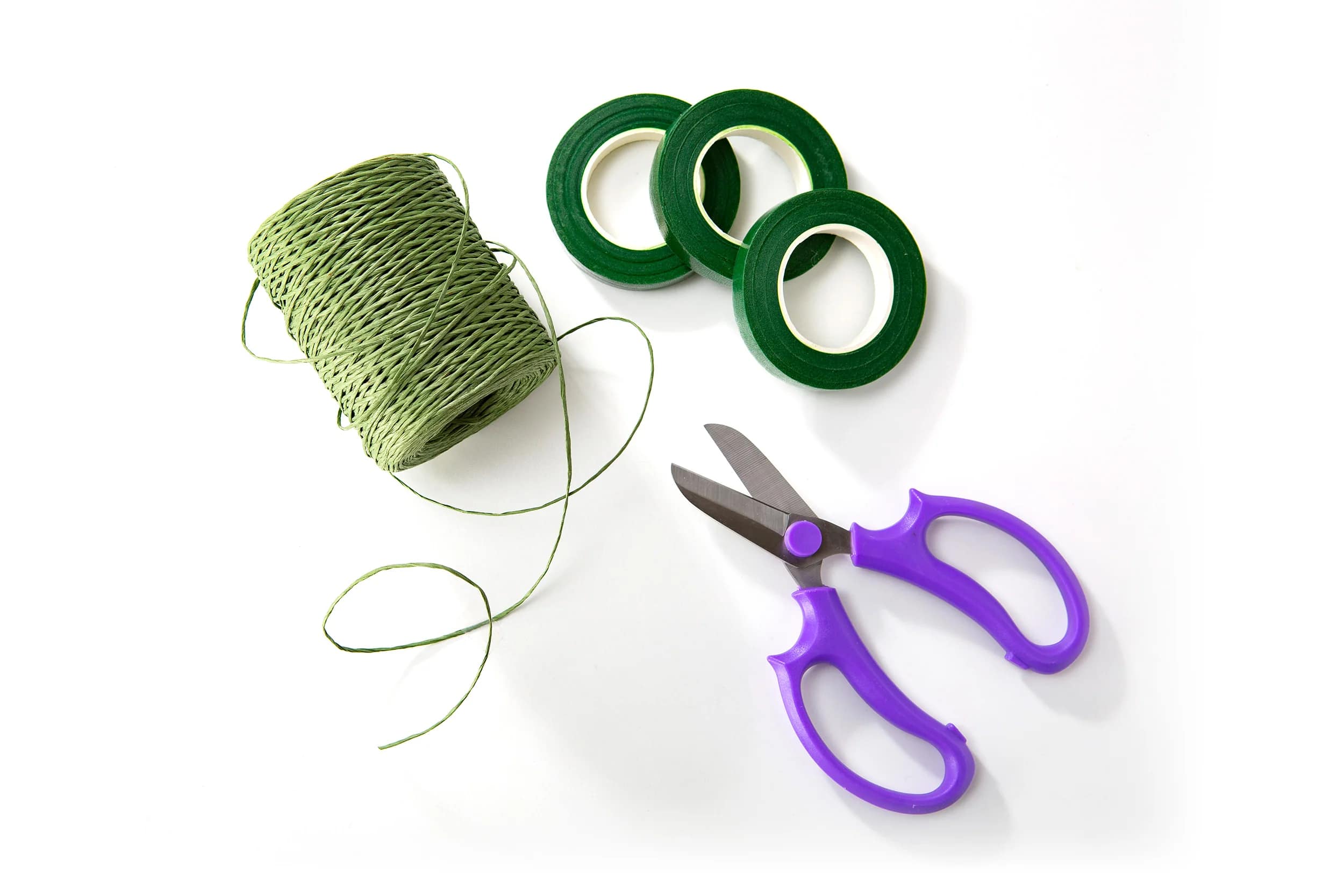 Green floral tape, twine, and purple-handled scissors on a white background