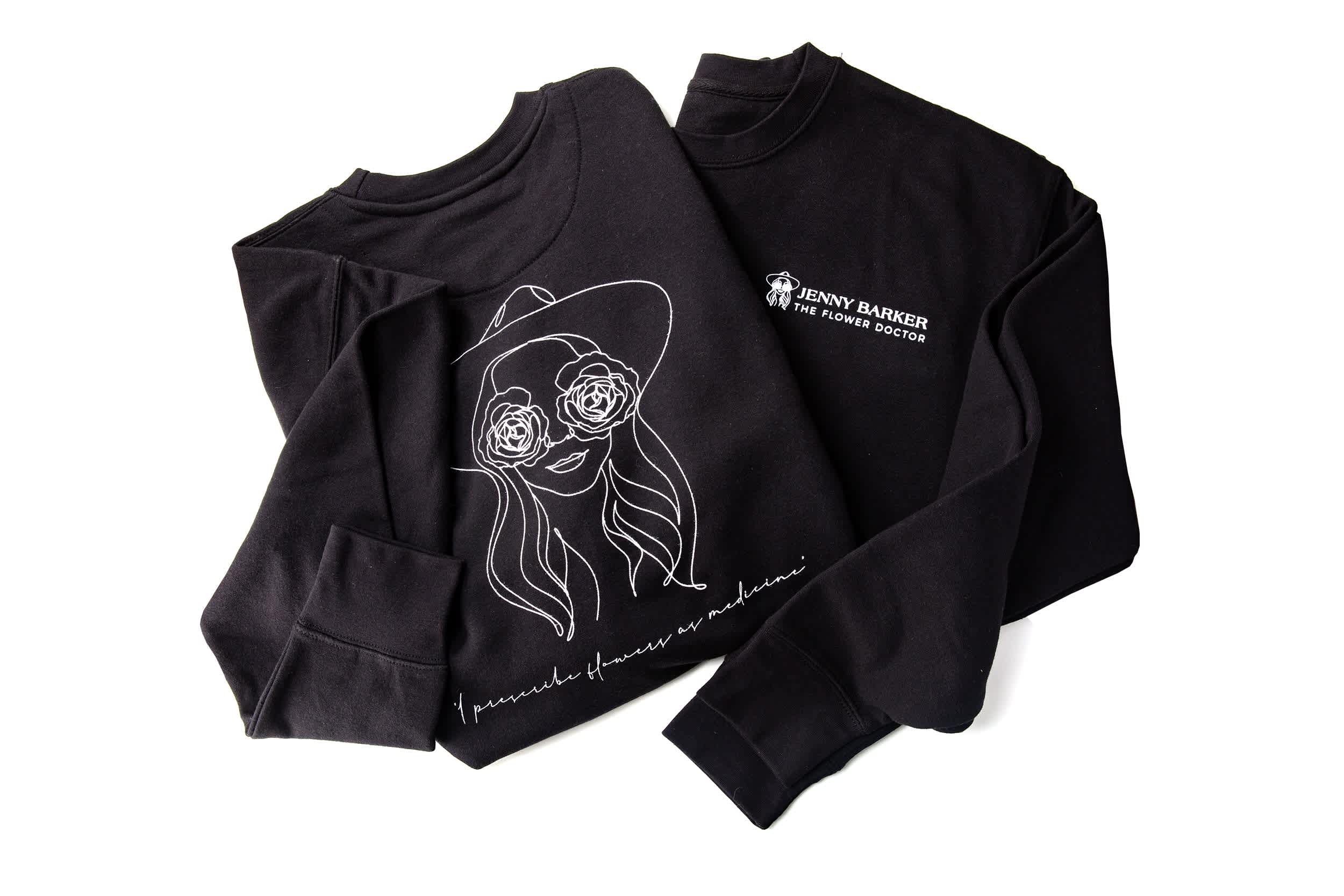Two black sweatshirts with white floral line art and text