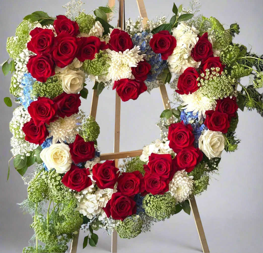 Heart-shaped floral wreath with red and white roses on a wooden easel