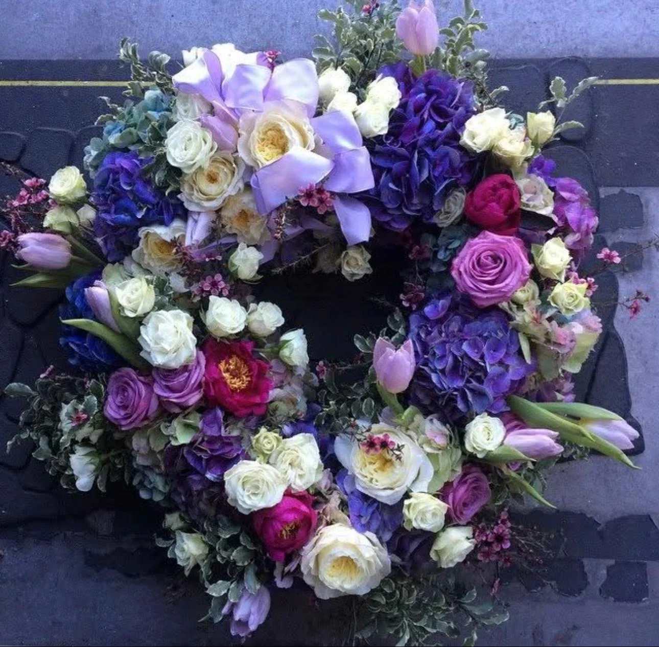 Circular floral wreath with purple, white, and pink blooms