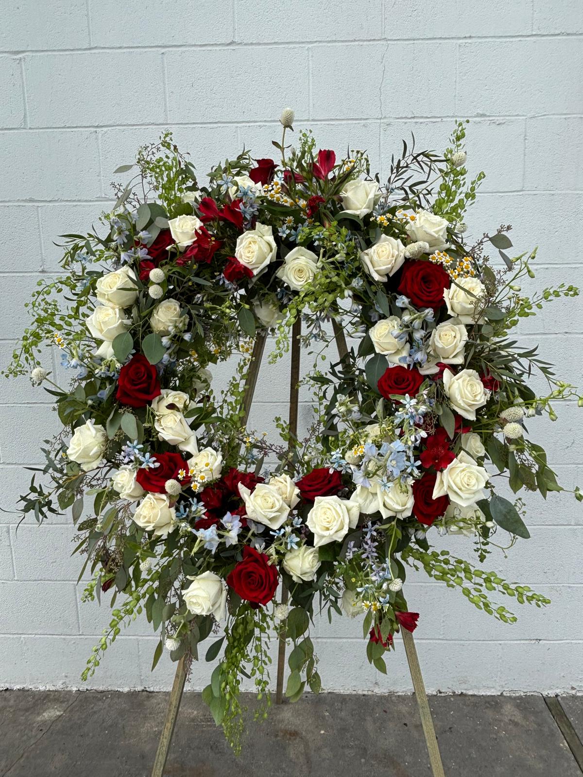 Large floral wreath of red and white roses on a stand