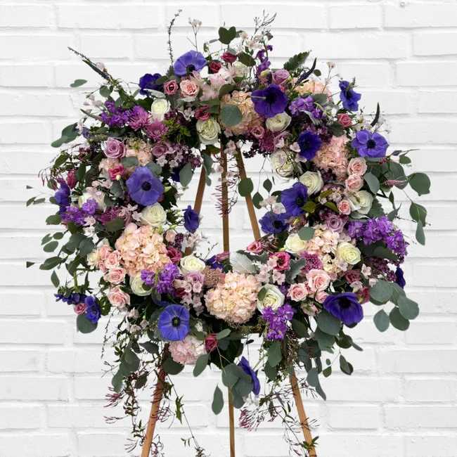 Large floral wreath on a wooden stand with purple, pink, and white blooms