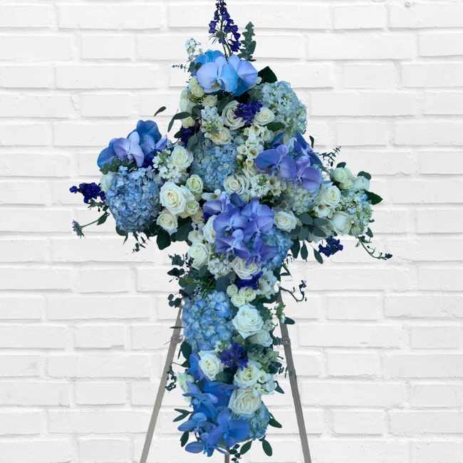 Blue and white floral cross arrangement on an easel