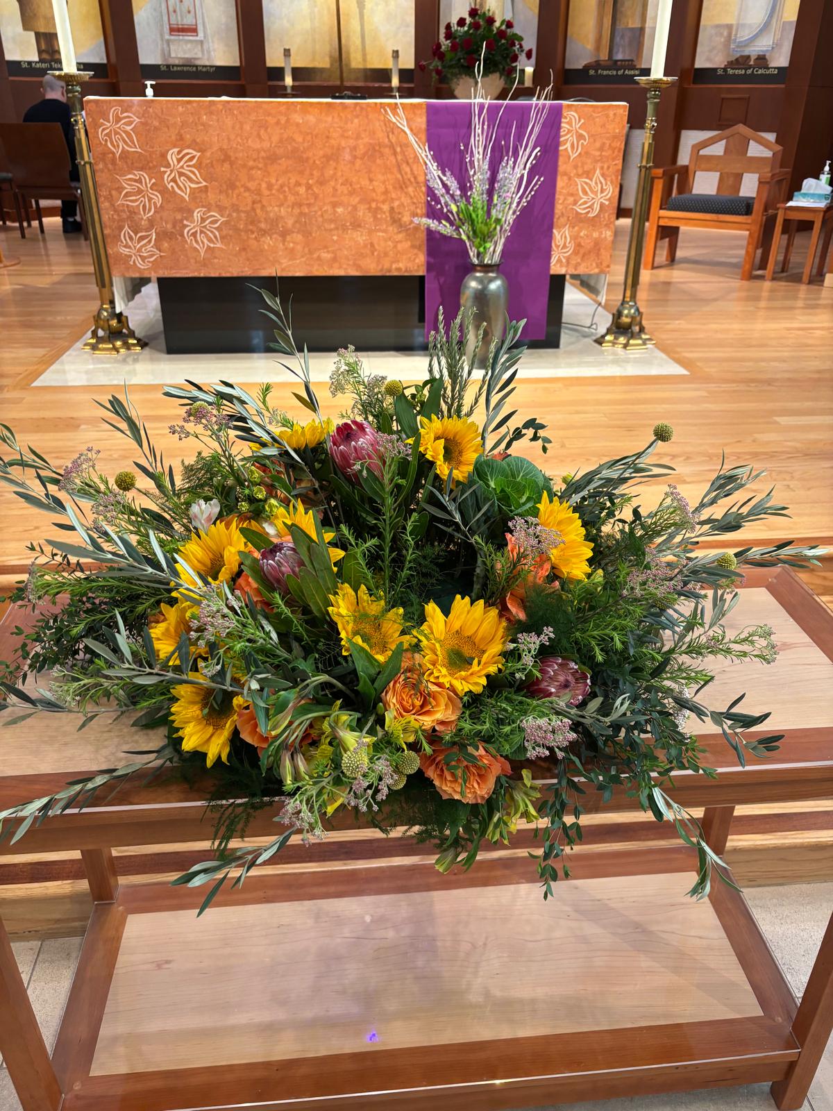 Large floral arrangement with sunflowers and orange blooms on a church altar