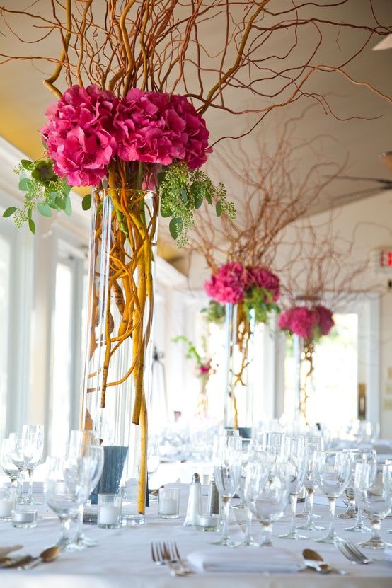 Tall pink floral centerpieces in clear glass vases on a banquet table