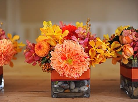 Orange and yellow floral arrangement in a square glass vase