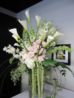Tall arrangement of white calla lilies and pale pink roses in a vase