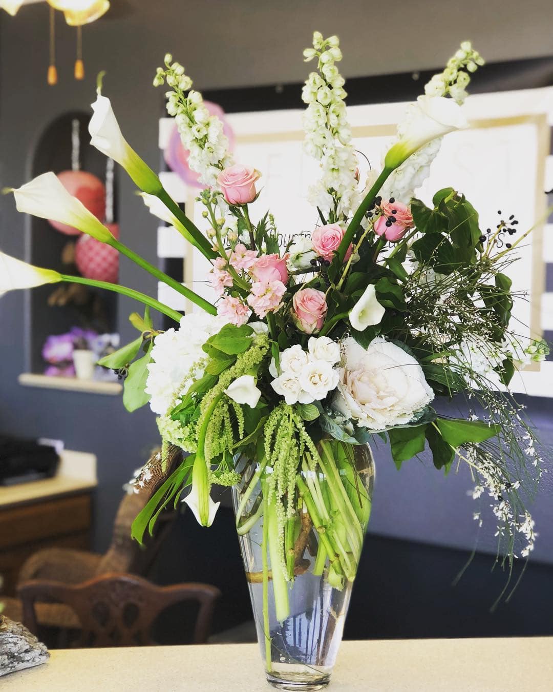 Tall floral arrangement with white calla lilies and pink roses in a glass vase