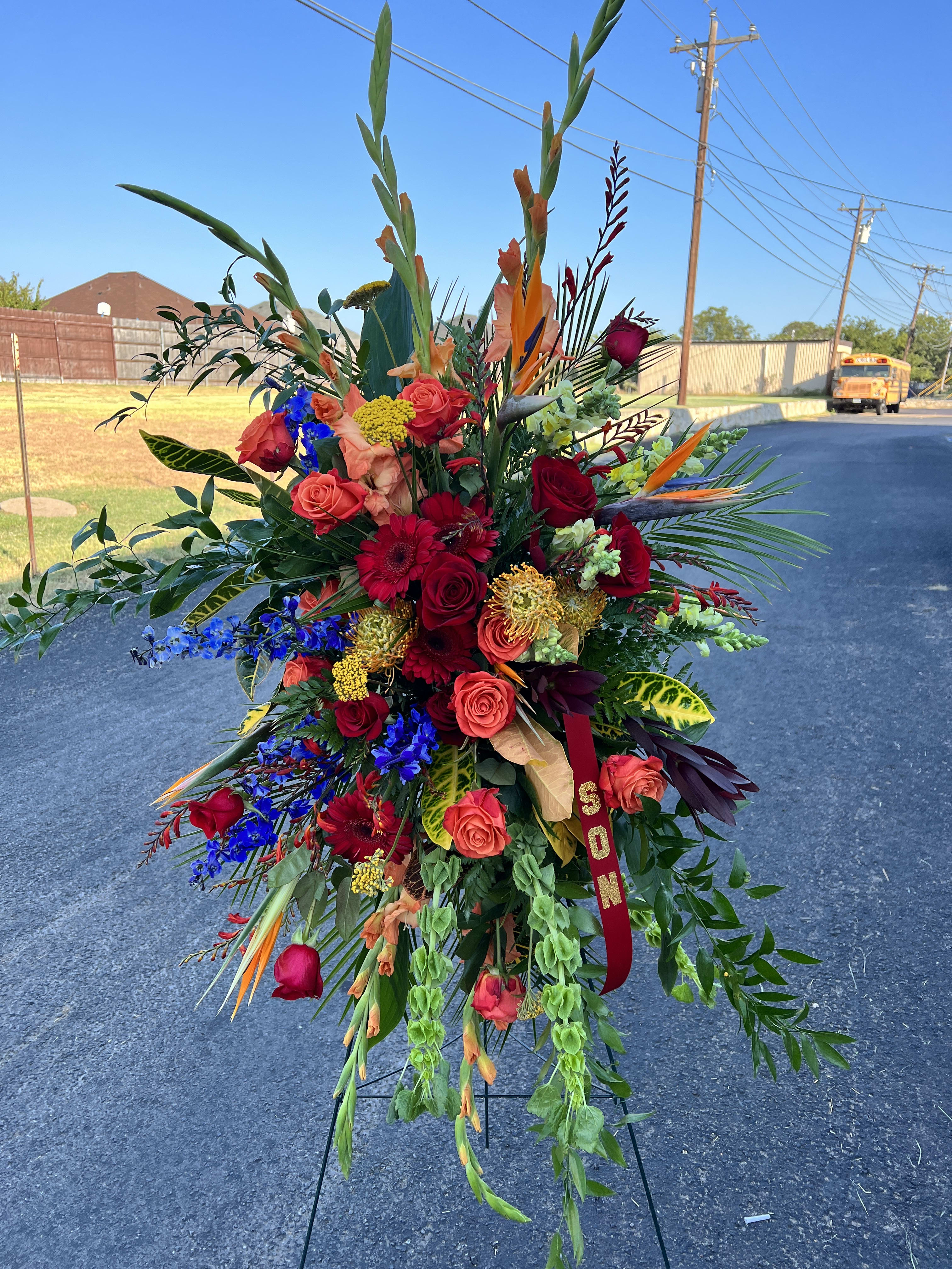 Large standing floral spray with red, orange, and blue flowers