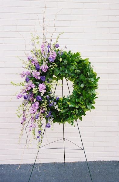 Large purple and green floral wreath on a metal stand