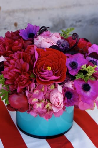Bright pink and red flower arrangement in a turquoise box