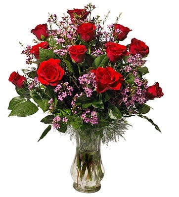 Bouquet of red roses and pink filler flowers in a clear glass vase