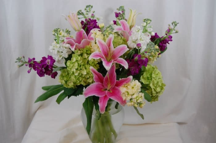 Pink lilies and mixed blooms in a clear glass vase