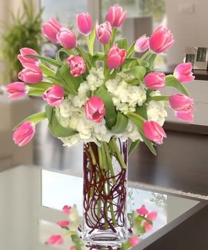Pink tulips arranged with white hydrangeas in a clear glass vase