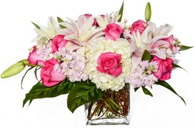 Pink roses and white lilies arranged in a clear glass vase