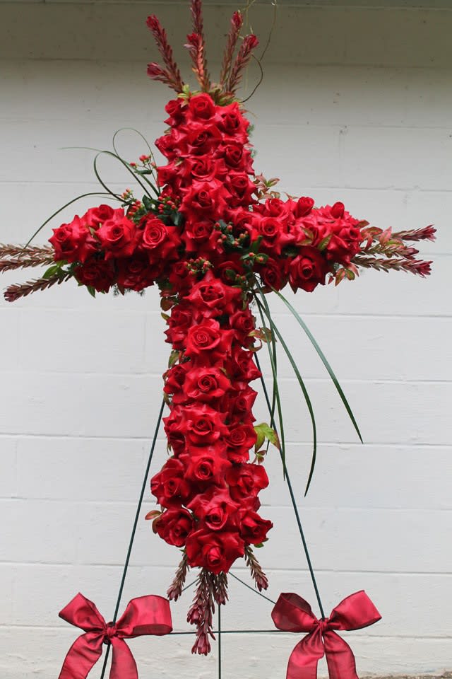 Red rose cross-shaped funeral spray on a stand with ribbon bows