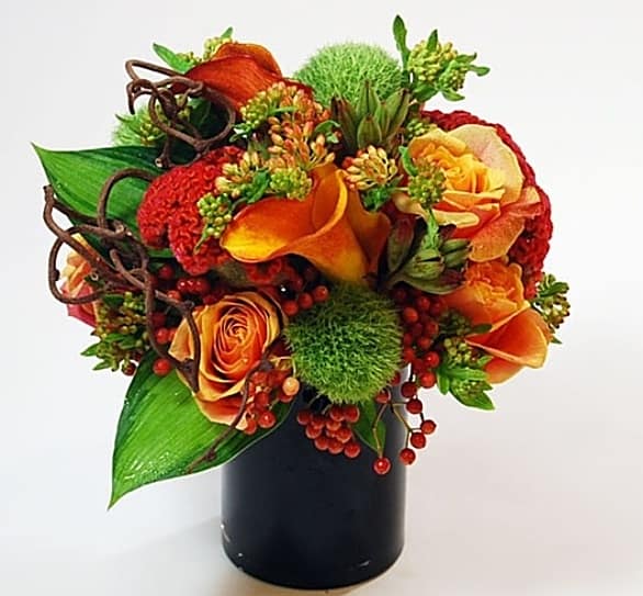 Orange and red floral arrangement in a black vase