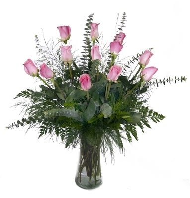 Pink roses arranged in a clear glass vase with greenery