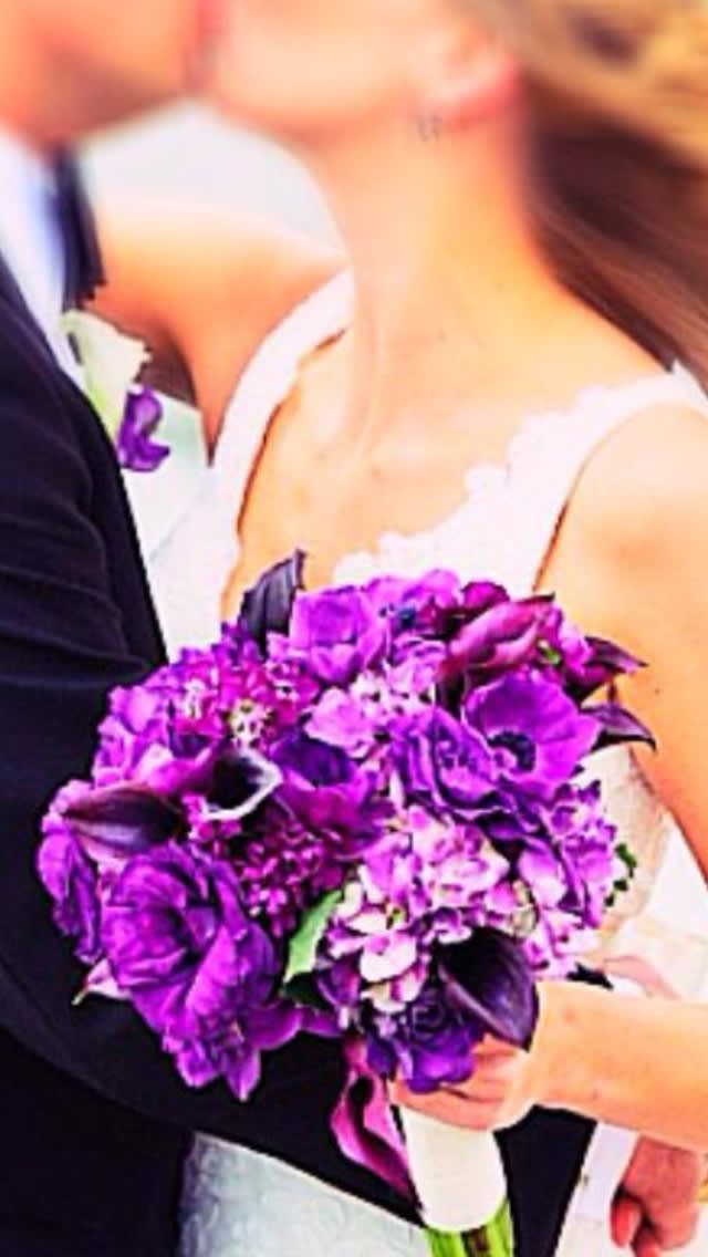 Bride holding a purple bouquet with white ribbon