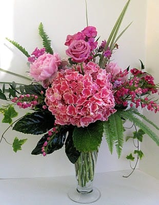 Pink floral arrangement in a clear glass vase with roses and hydrangea