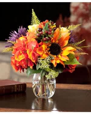 Bright autumn bouquet in a clear glass vase with sunflowers and orange blooms
