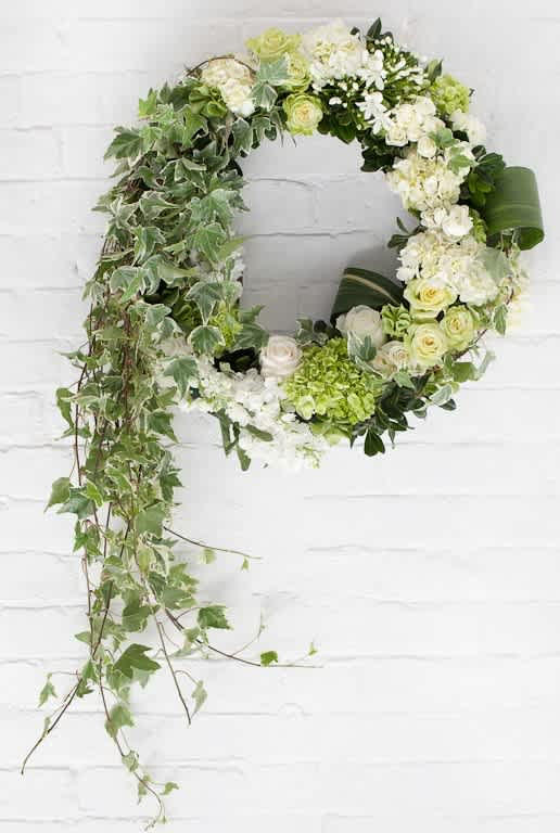 Circular floral wreath with white and green flowers and trailing ivy