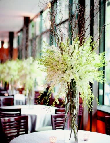 Tall white floral centerpiece in a clear vase with curly branches