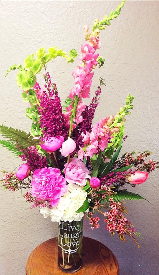 Pink and white floral arrangement in a glass vase with tall green spikes