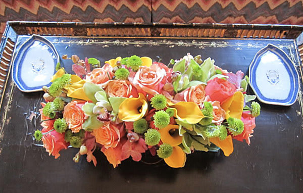 Low floral centerpiece with roses and calla lilies on a dark tray
