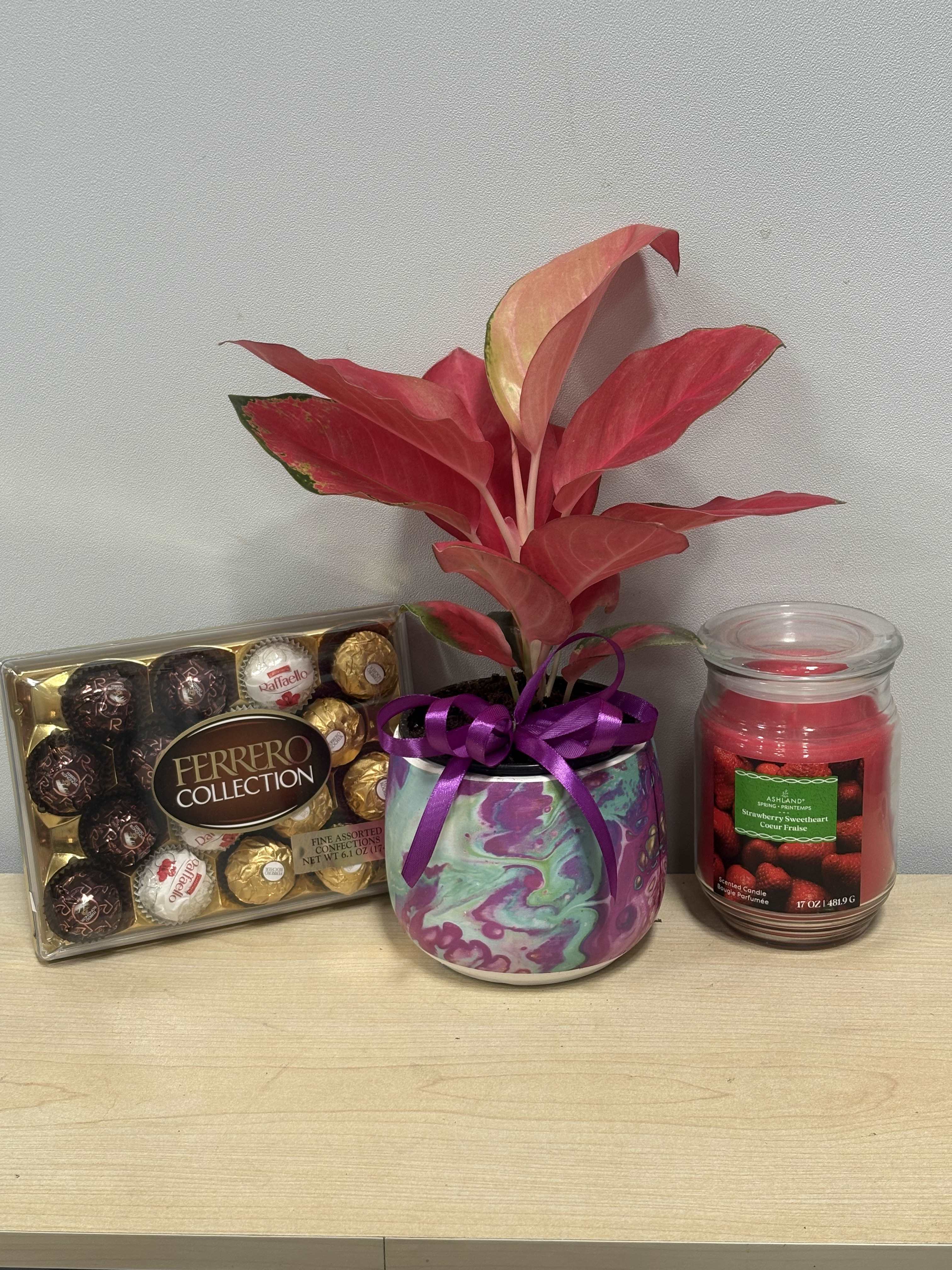 Potted pink-red plant with chocolates and a strawberry candle