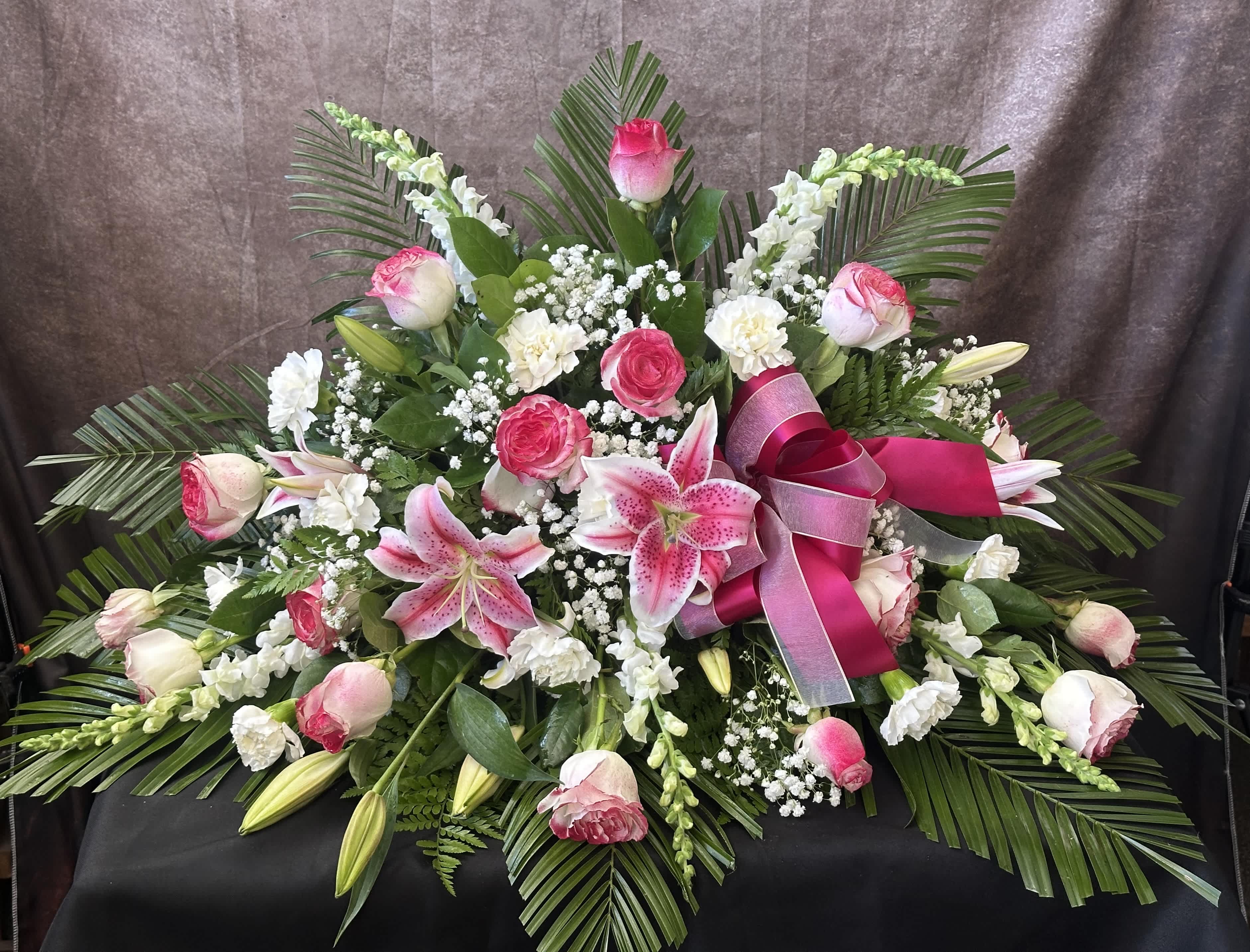 Pink and white floral spray with lilies, roses, and ribbon