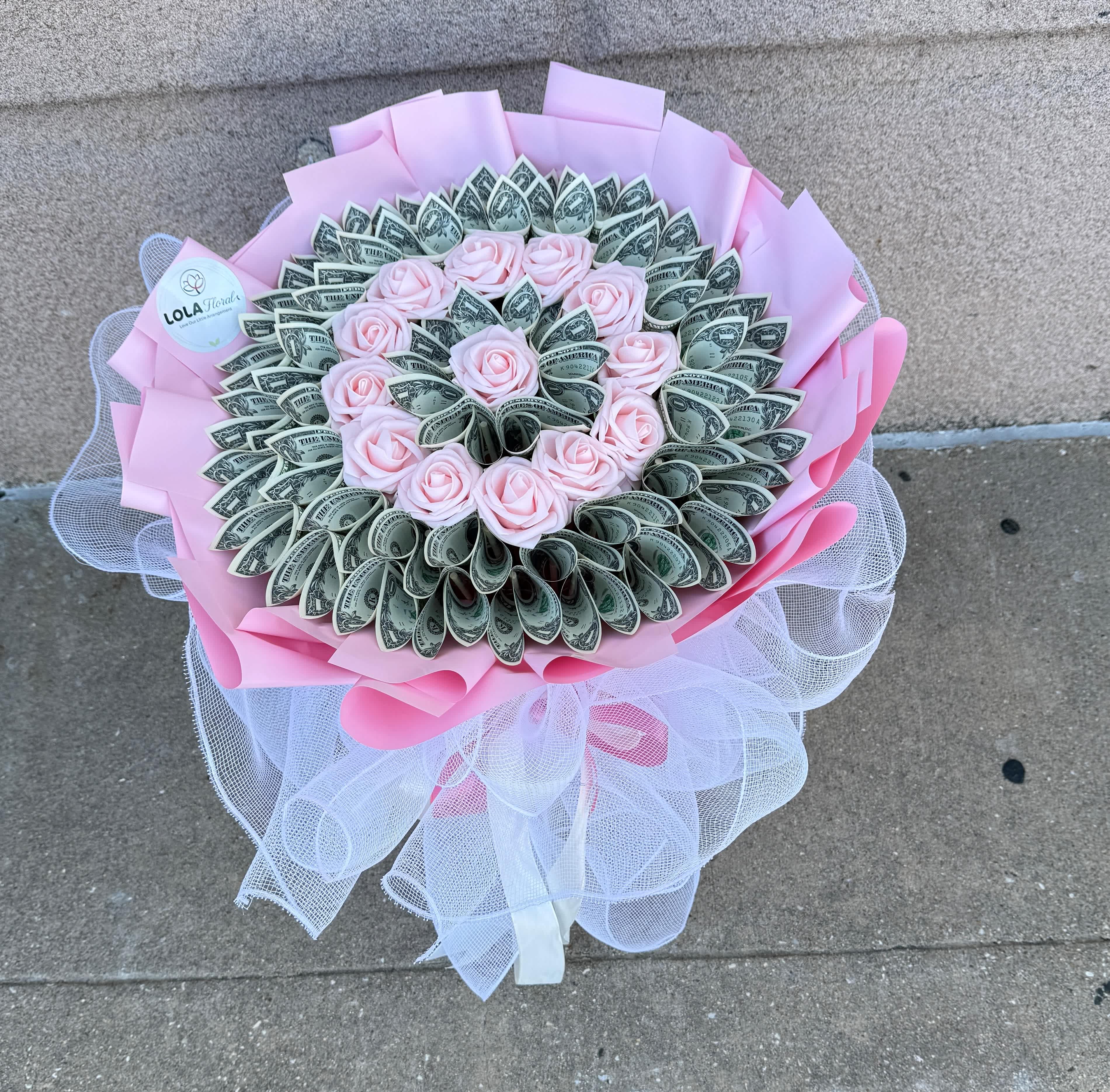 Bouquet of pink roses and folded dollar bills wrapped in pink paper and white mesh