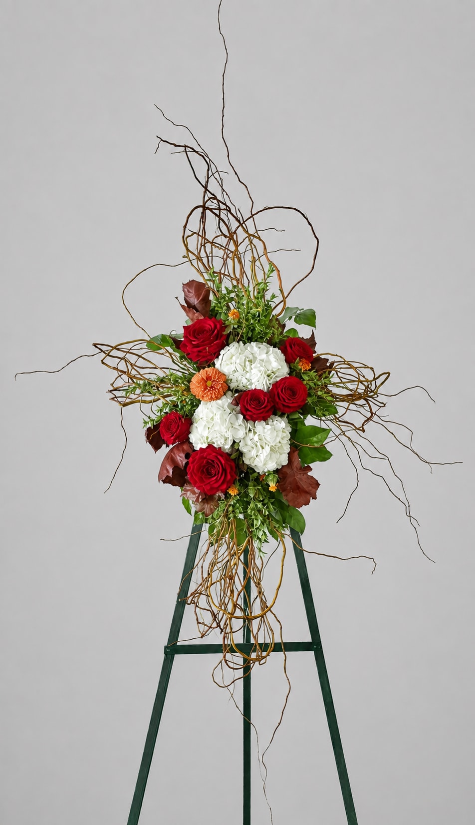 Tall floral arrangement with red roses and white hydrangeas on an easel