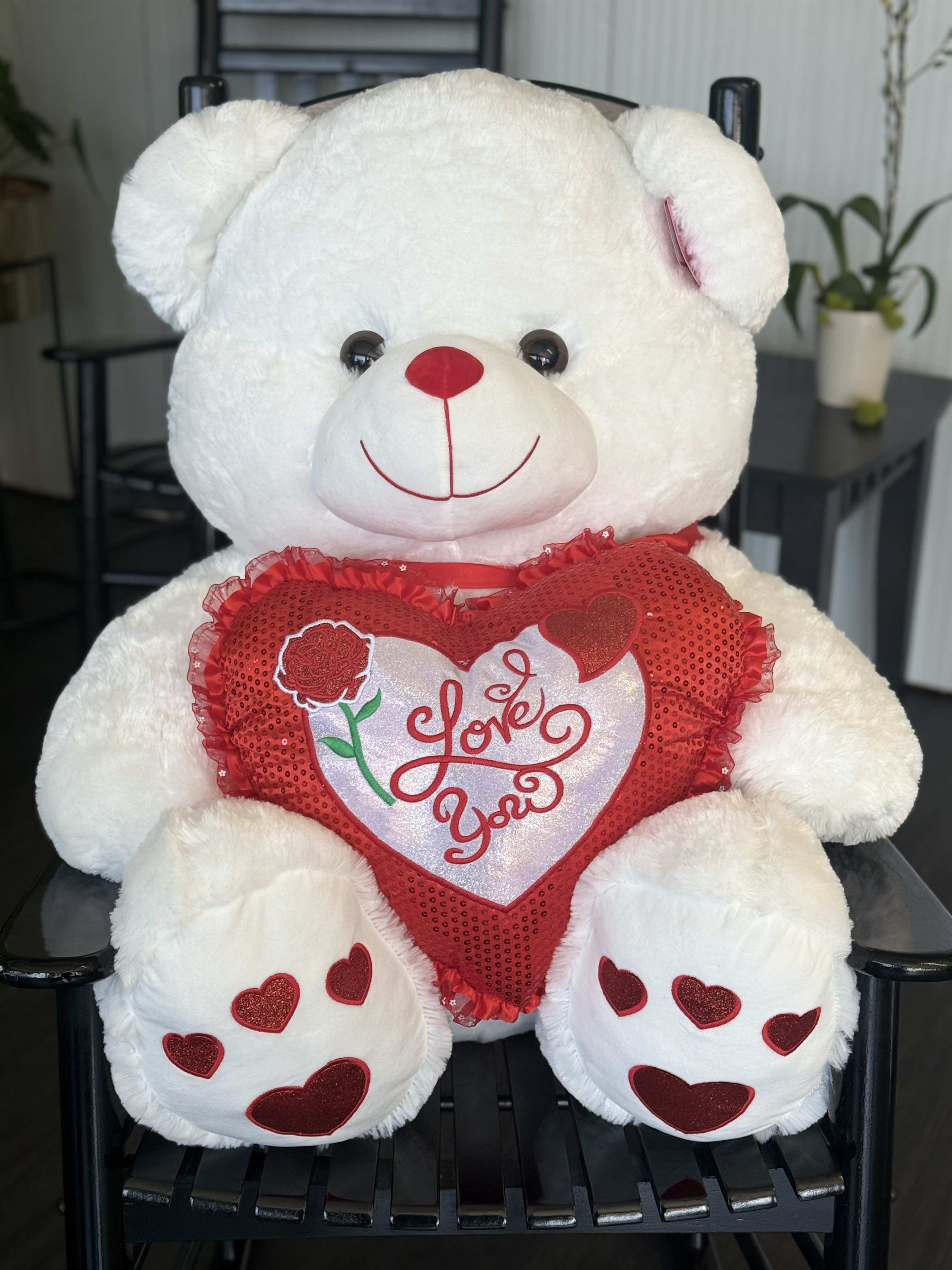 White teddy bear holding a red heart pillow with "Love You" text