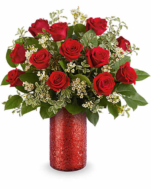 Red roses arranged in a red vase with white filler flowers