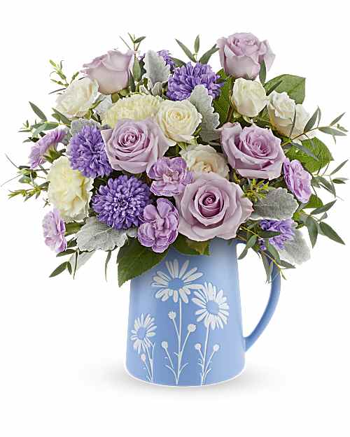 Lavender roses and purple flowers in a blue pitcher vase