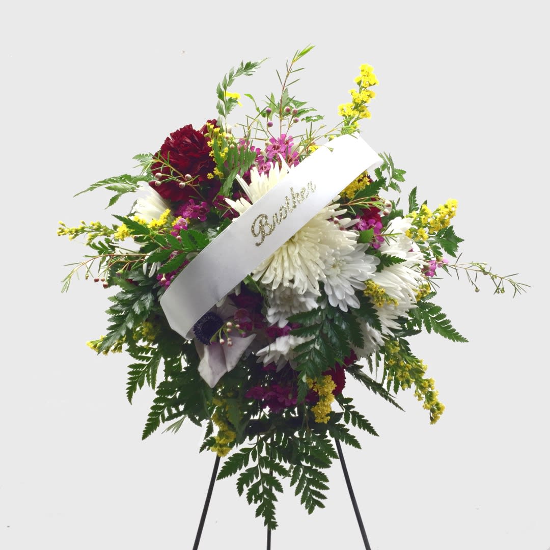 Standing floral spray with white and burgundy flowers and a white ribbon