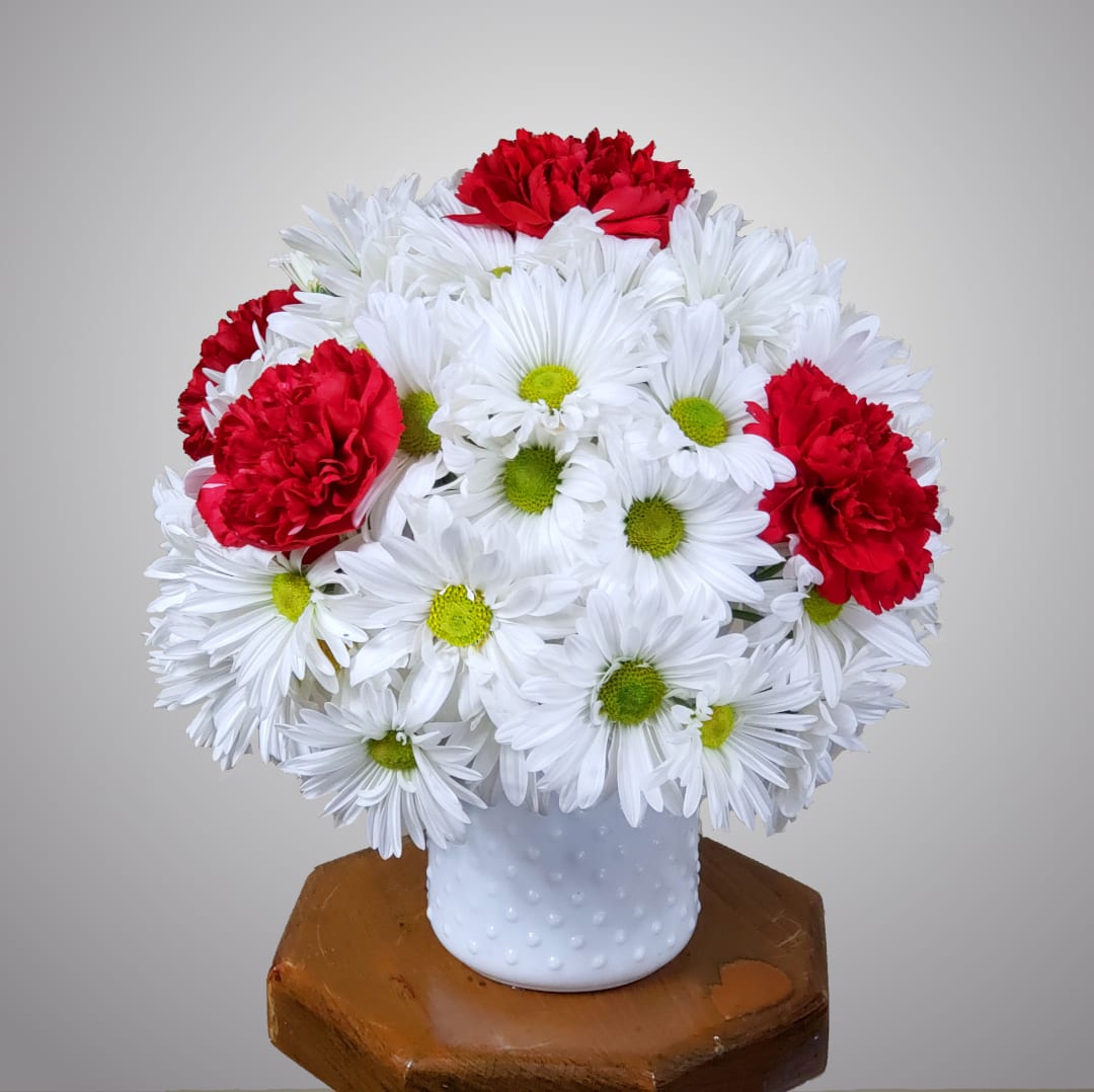 White daisies and red carnations arranged in a white vase