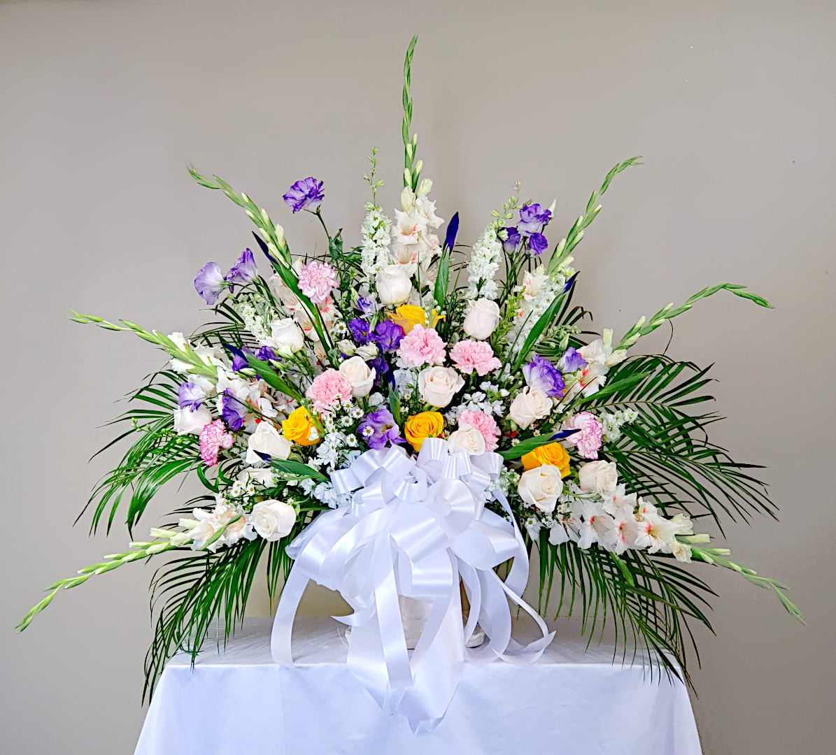 Large floral arrangement with white, pink, purple, and yellow blooms in a white container
