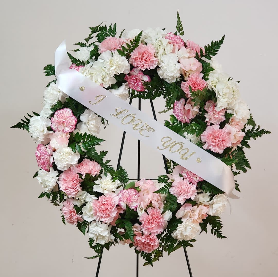 Pink and white carnation wreath with a ribbon reading "I love you"