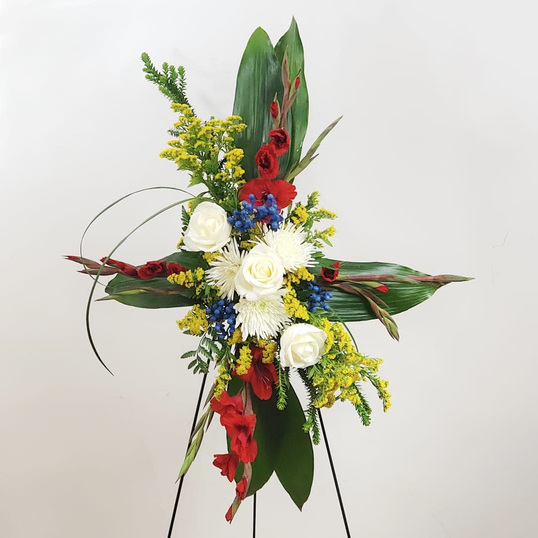 Tall floral standing spray with red, white, yellow, and blue flowers