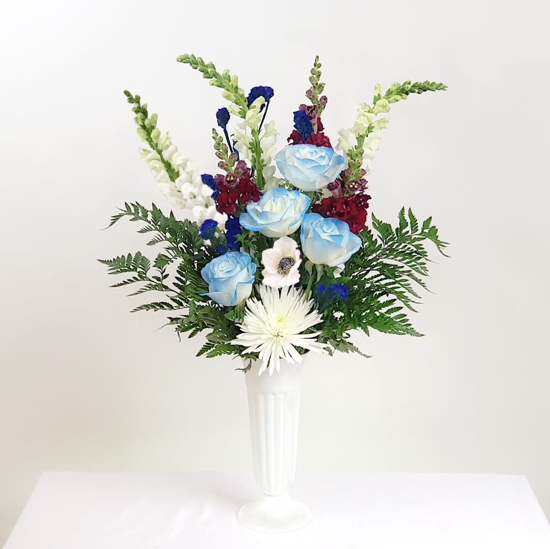 Blue and white flowers arranged in a tall white vase
