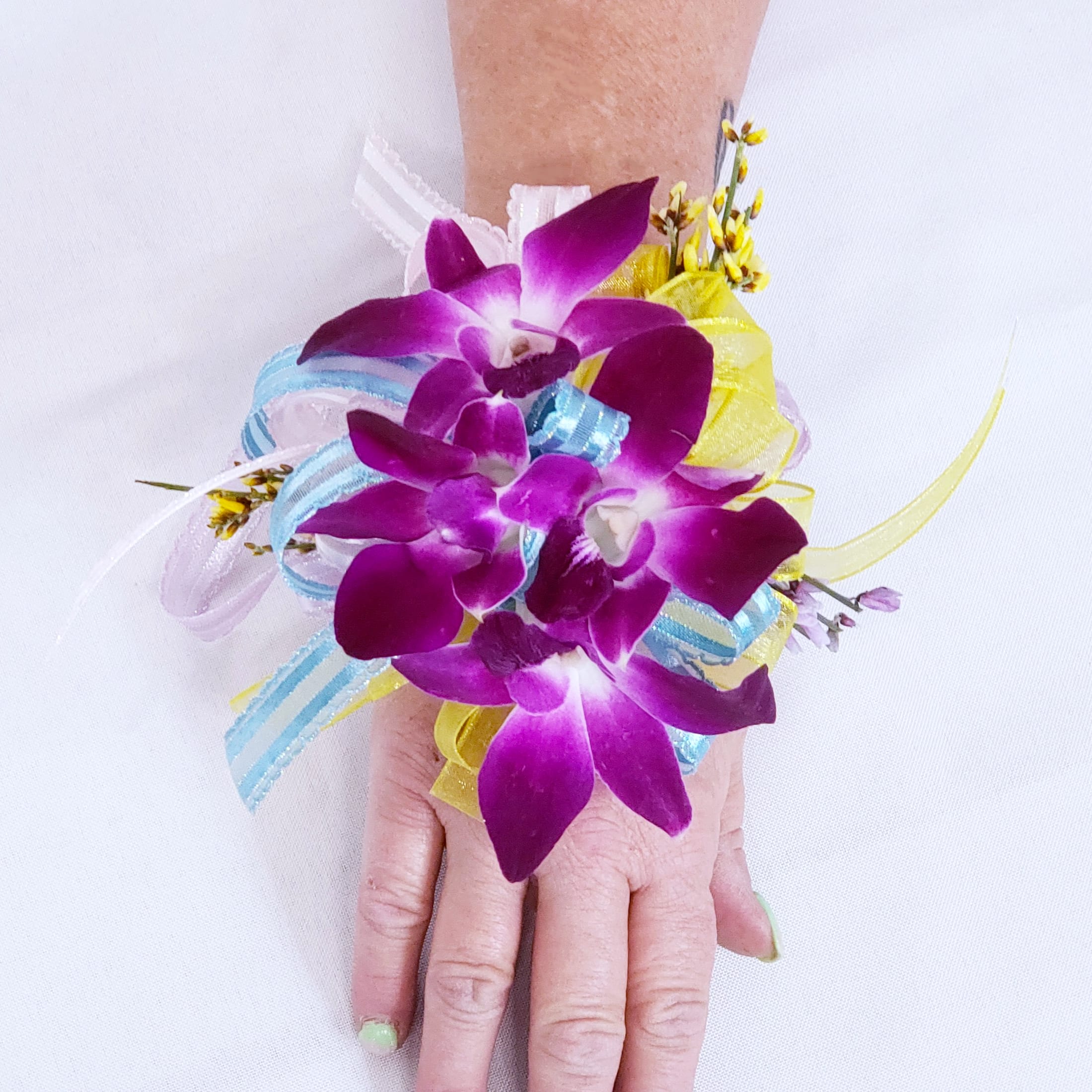 Purple orchid wrist corsage with blue and yellow ribbon accents