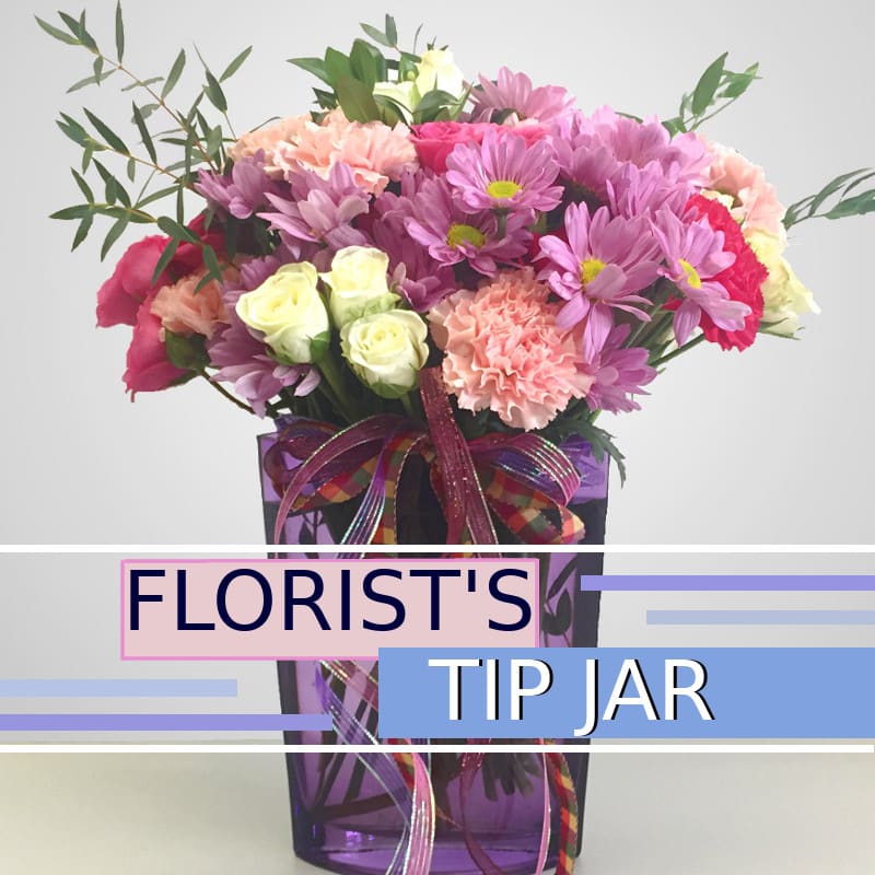 Mixed pink and purple flowers in a purple vase with ribbon