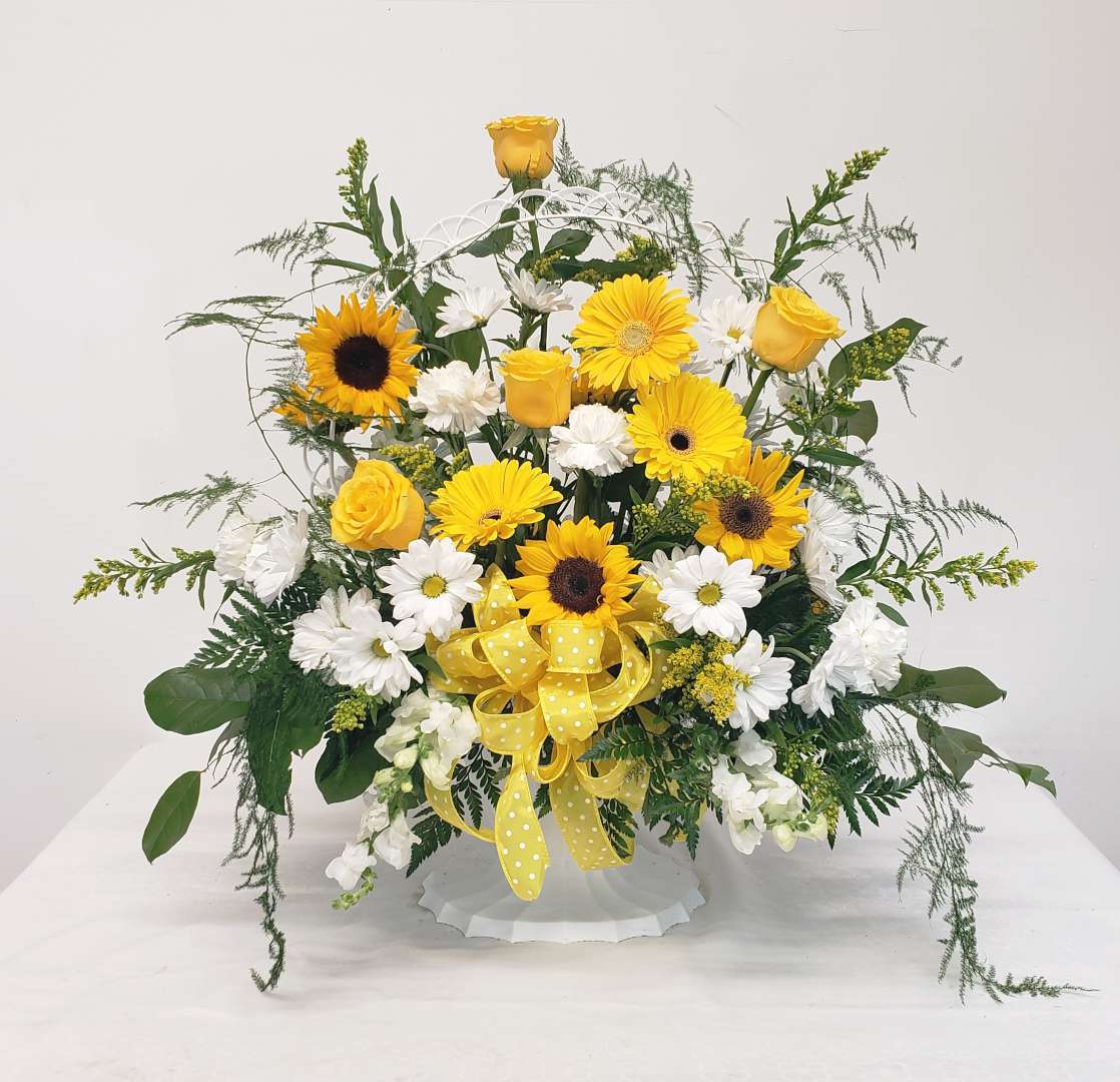 Yellow roses and sunflowers with white daisies in a white basket