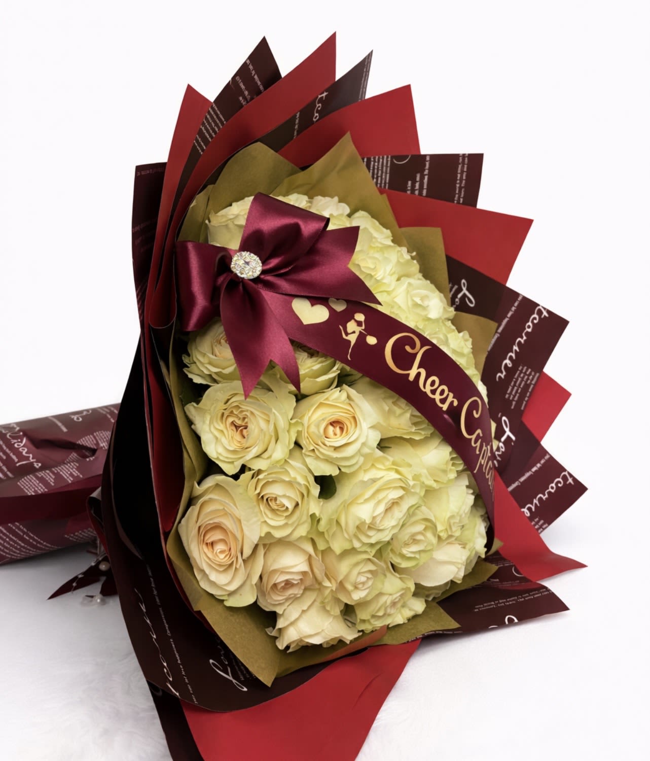 Bouquet of cream roses wrapped in burgundy and red paper with a satin bow