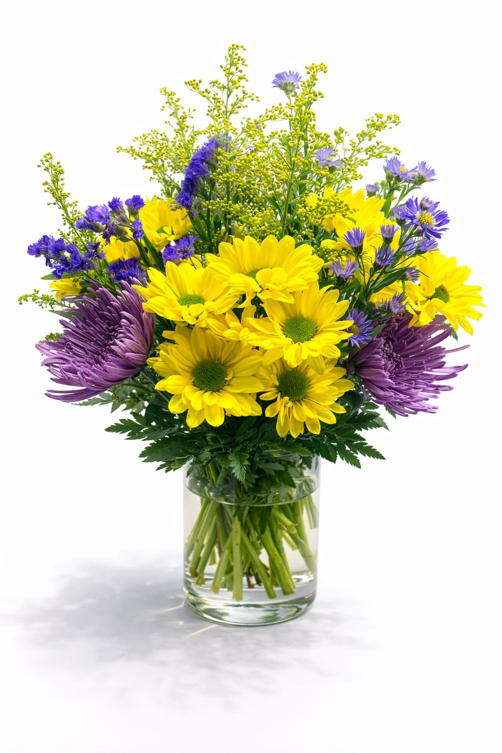 Yellow and purple flowers arranged in a clear glass vase